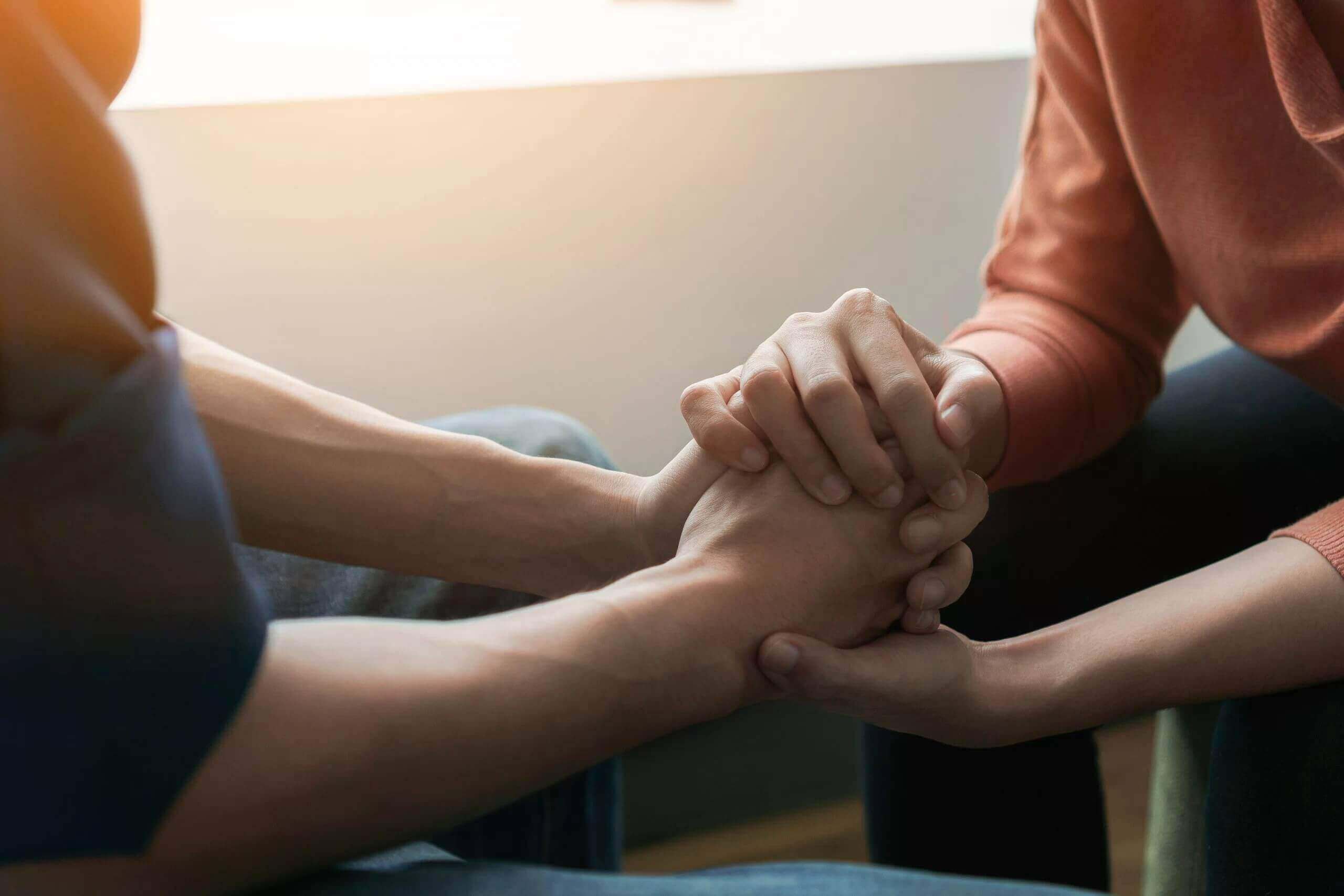 Two people holding hands in a supporting manner