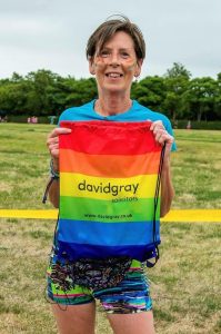 A lady holding up a bag with the Pride Flag and the David Gray logo on the bag